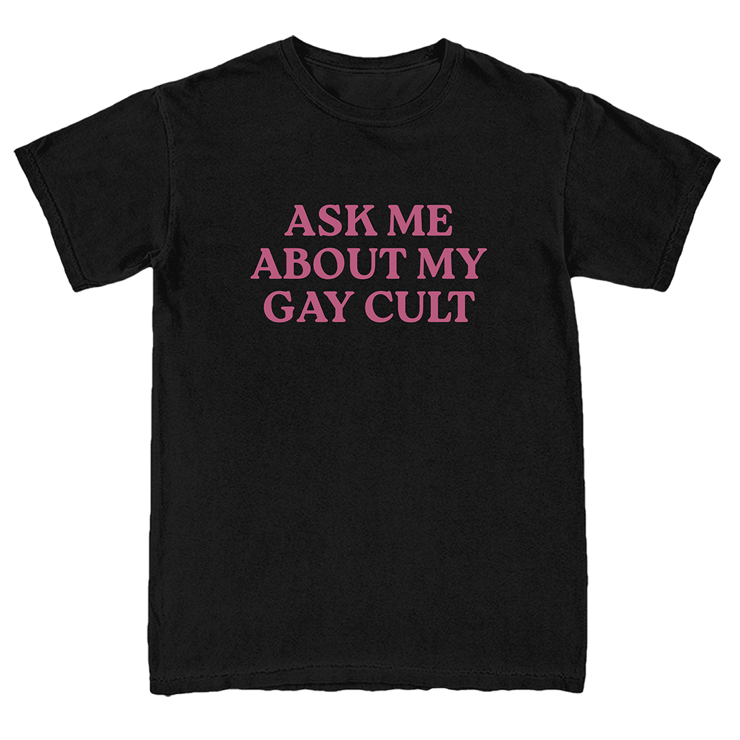 A black short-sleeve crewneck t-shirt with the phrase 'ASK ME ABOUT MY GAY CULT' printed in pink serif capital letters across the chest.